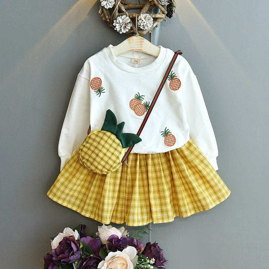 Embroidered sweater and plaid skirt suit with pineapple motifs and matching bag.